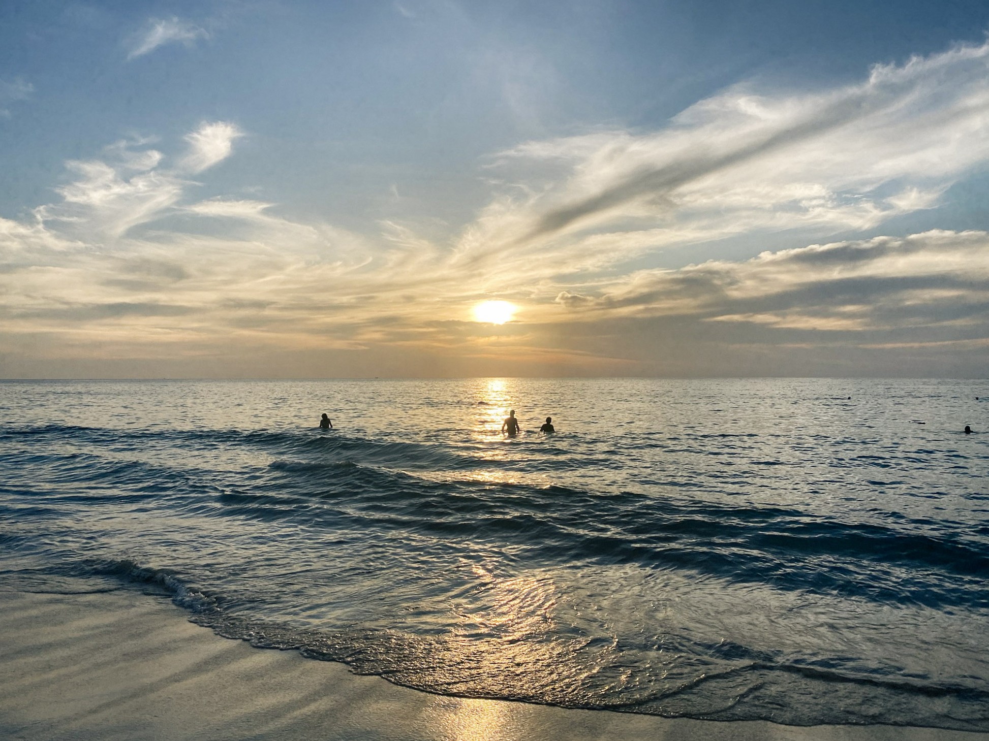 The sun beginning to dip over the sea at Surin Beach, Phuket, Thailand.